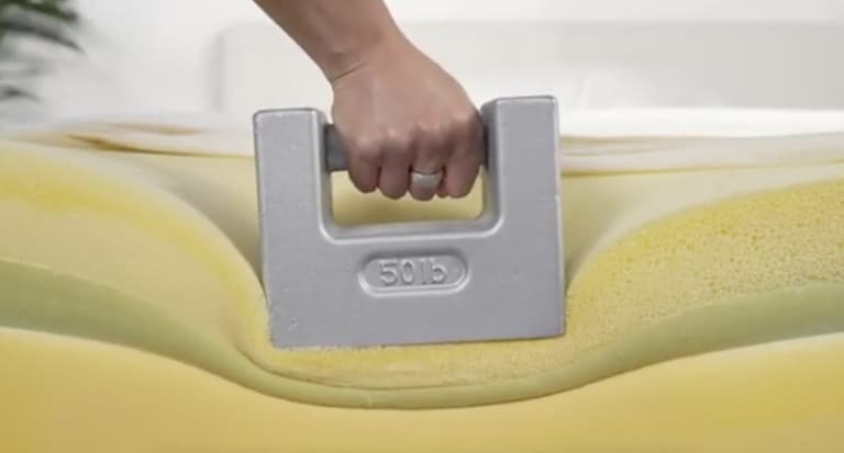 50-pound weight compressing a mattress foam layer during Sleep Foundation testing
