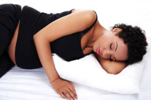 A pregnant woman sleeps peacefully on her side